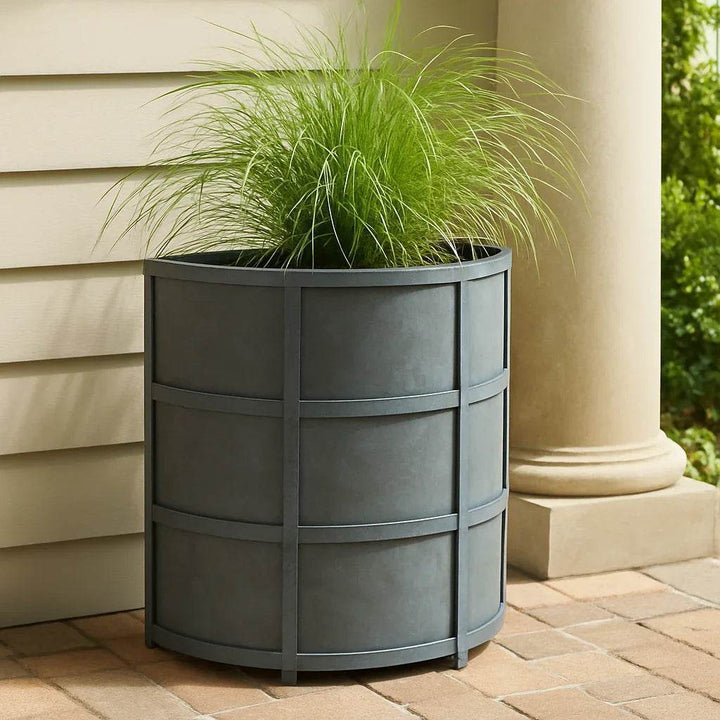 Half-round antique gray iron planter styled outdoors with lush greenery, showing modern heritage look in a garden setting.

