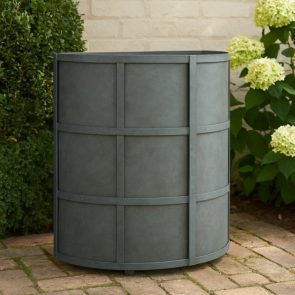 Antique gray iron planter styled in a modern heritage garden setting with surrounding greenery and stone pavers.


