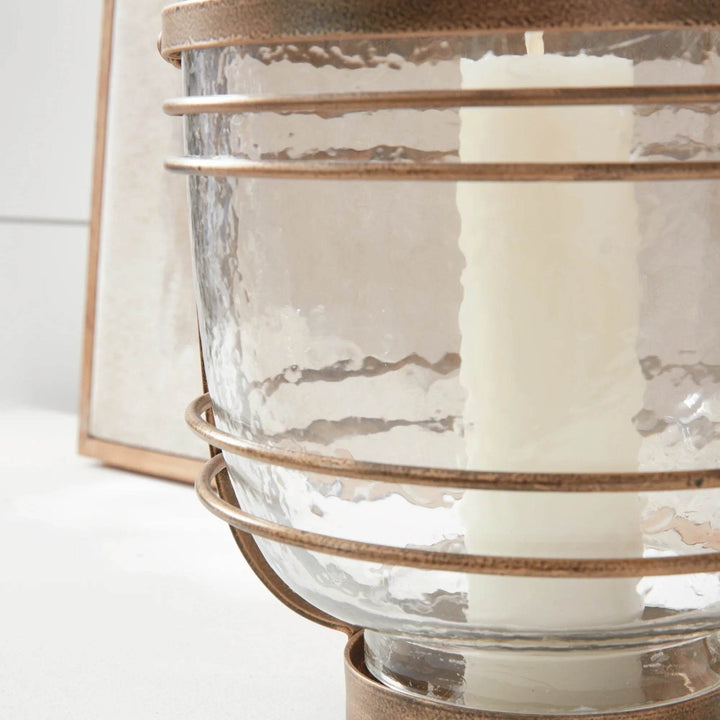 Close up of hammered glass hurricane showing antique gold iron base and banded frame, vessel for pillar candle – Coastal