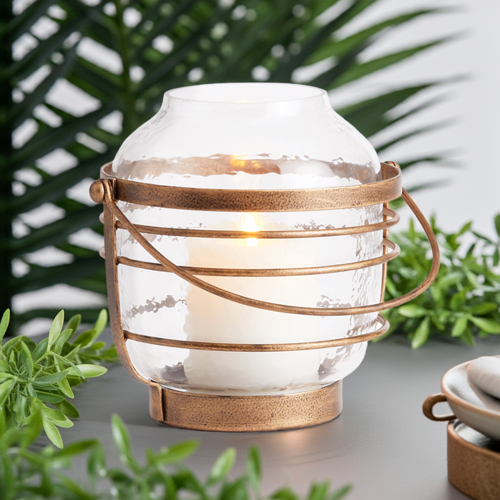 Medium hammered glass hurricane with antique gold iron frame, displayed outdoors with plants and greenery – Coastal