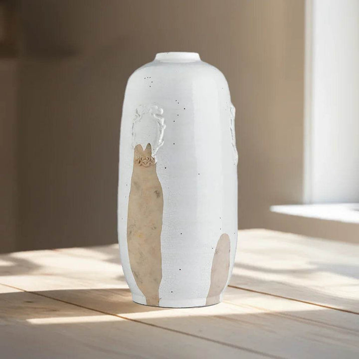 Handcrafted white ceramic vase with clay detail styled on a table near window, adding artisan texture to interior decor.

