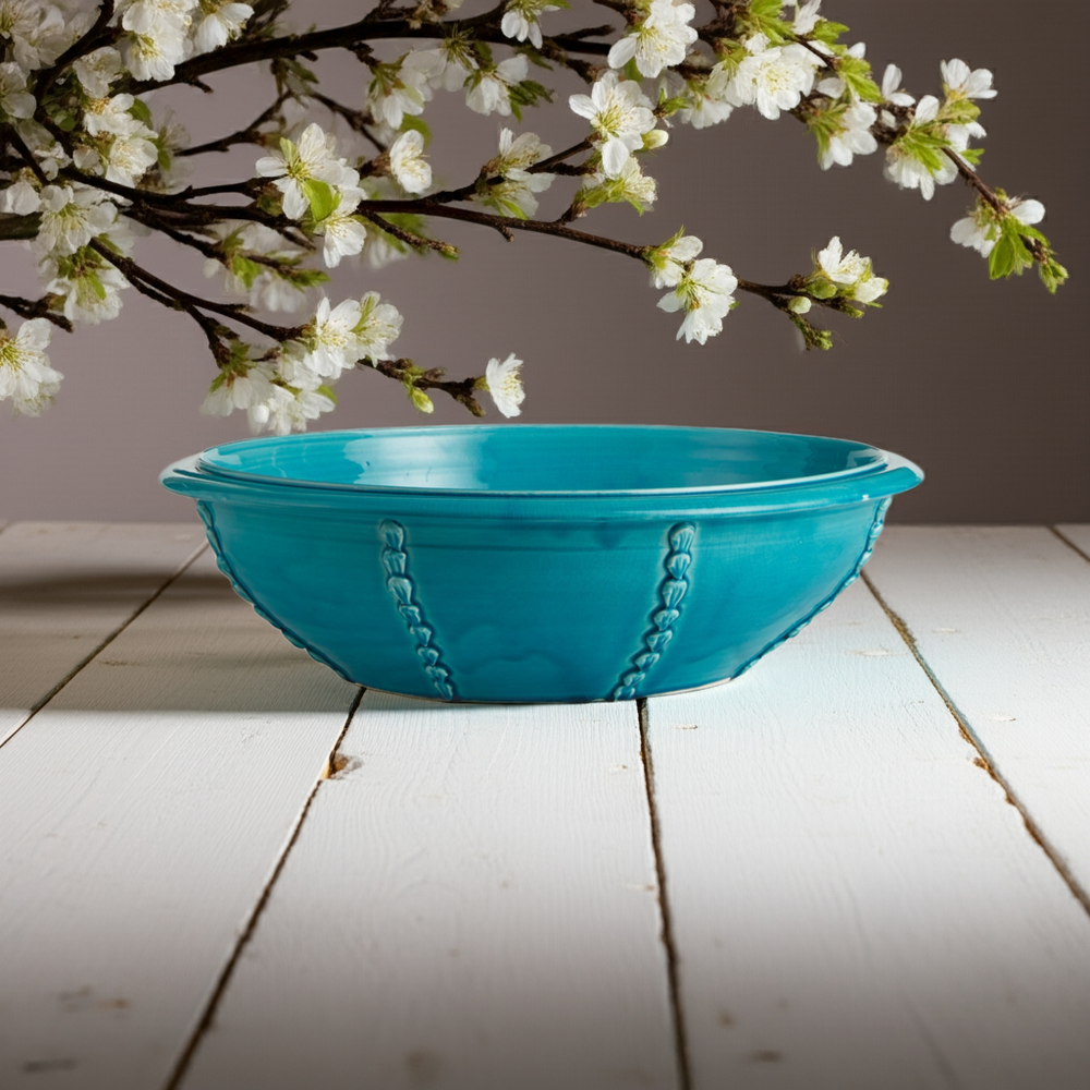 Large artisan aqua ceramic bowl styled with florals on neutral wood table