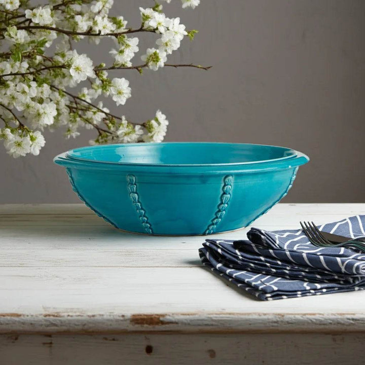 Mediterranean glazed ceramic bowl in aqua styled with towel and spring stems

