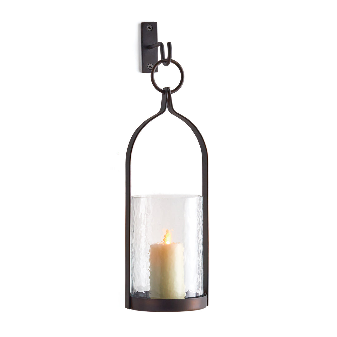 Harlan black and bronze wall lantern with an iron frame, hammered glass candle insert and hanging hook on white. Transitional