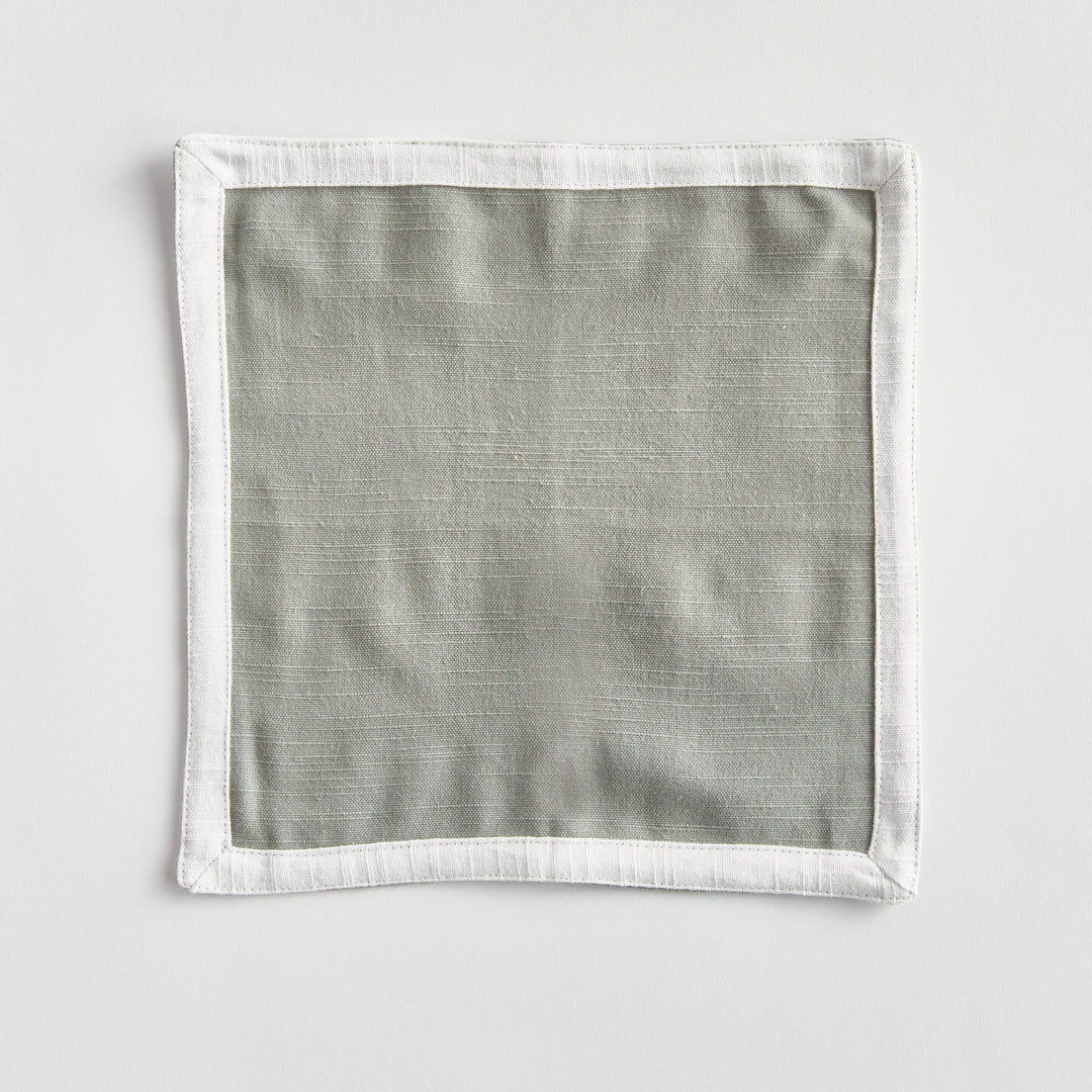 Green and white cocktail napkins, shown open as a square, with a white border framing green woven cotton panel. Transitional