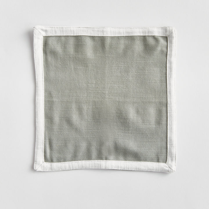 Green and white cocktail napkins, shown open as a square, with a white border framing green woven cotton panel. Transitional