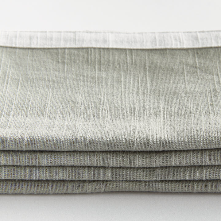 Green and white dinner napkins, close detail showing the cotton weave and border above folded fabric. Classic Transitional