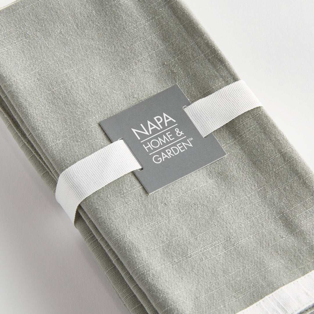 Green and white dinner napkins, close view of the set tied with ribbon, showing the border and woven surface. Transitional