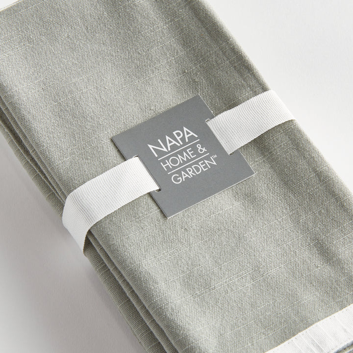 Green and white dinner napkins, close view of the set tied with ribbon, showing the border and woven surface. Transitional