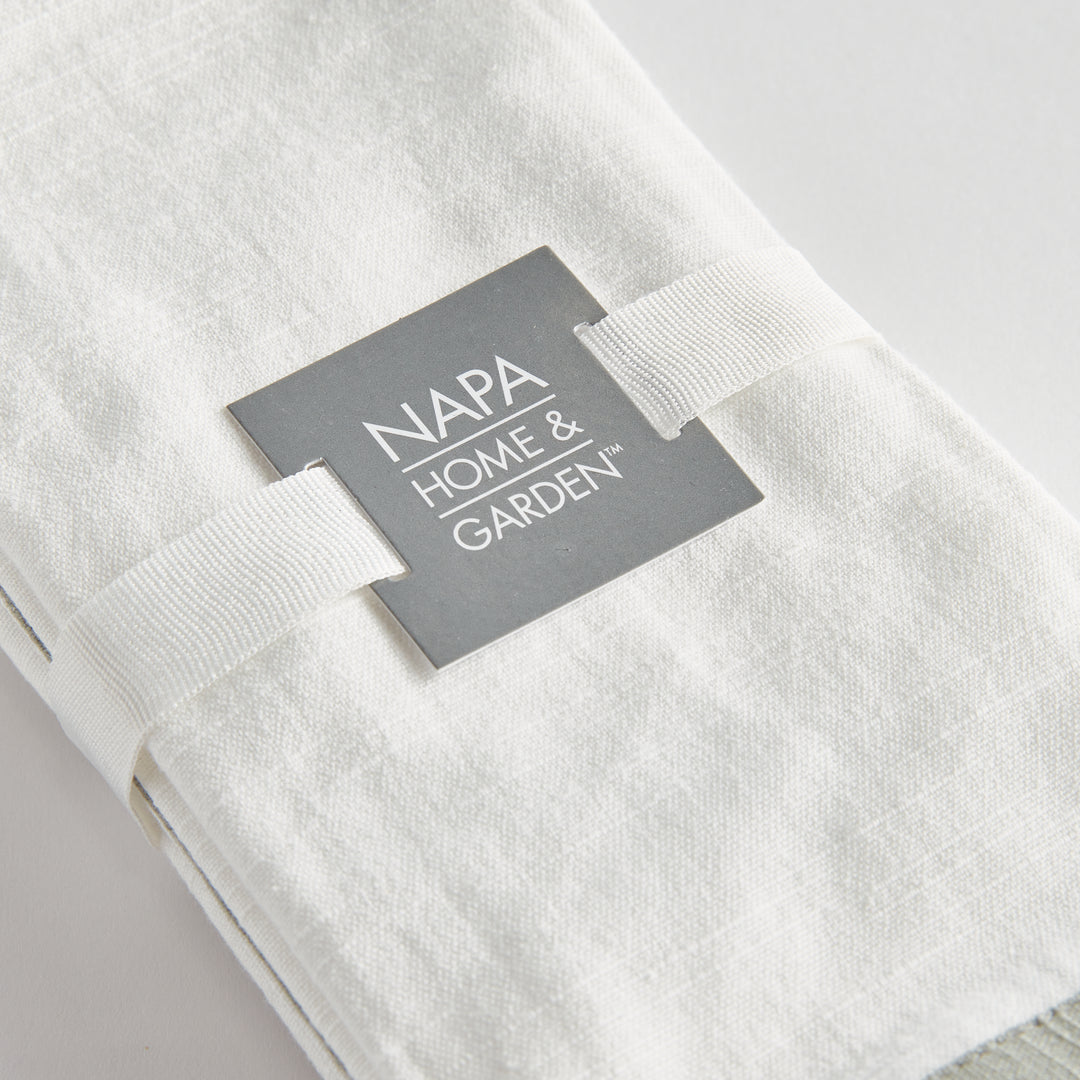 White and sage dinner napkins, close view of the set tied with ribbon, showing the border and woven surface. Transitional