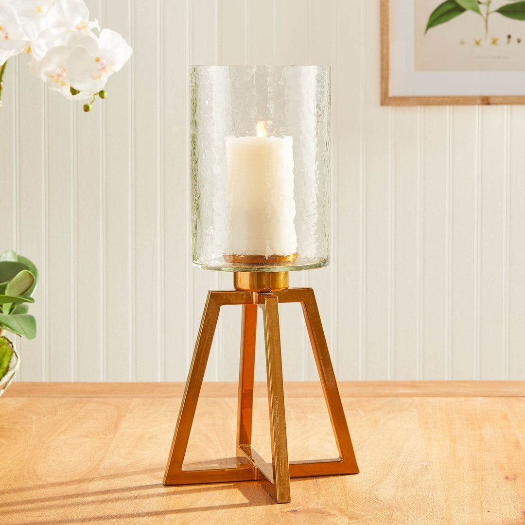 Gold metal hurricane candle holder with hammered glass, styled on a console with orchid and frame – Industrial Modern

