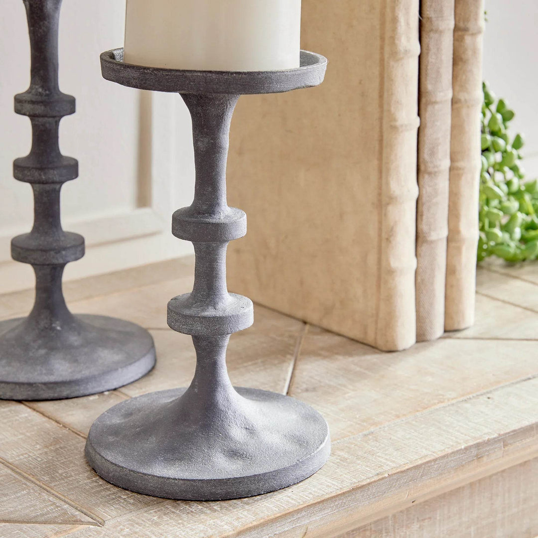 Pair of industrial black candle stands photographed from angle, highlighting height difference and notched columns – Contemporary