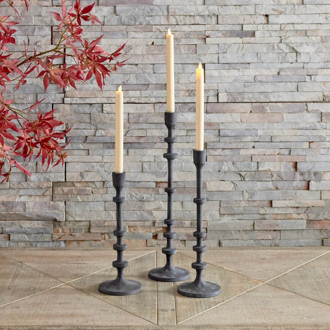 Set of 3 industrial black taper candle holders styled outdoors against stone wall with tall candles – Industrial Decor