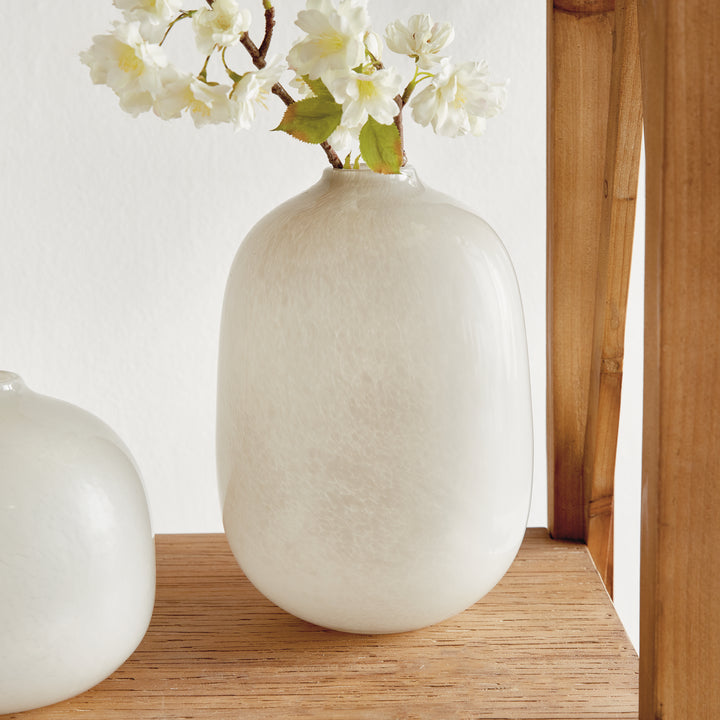 Ivory glass vase family on wood, with a tall flower-filled vase and a round companion partly visible, Modern Organic style