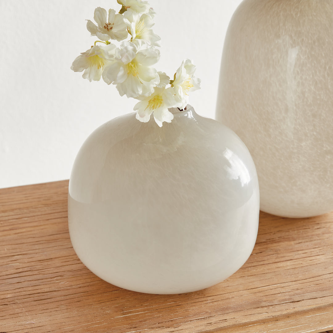 Ivory round glass vase holding decorative flowers on wood, with a taller coordinating vase beside it, Modern Organic style