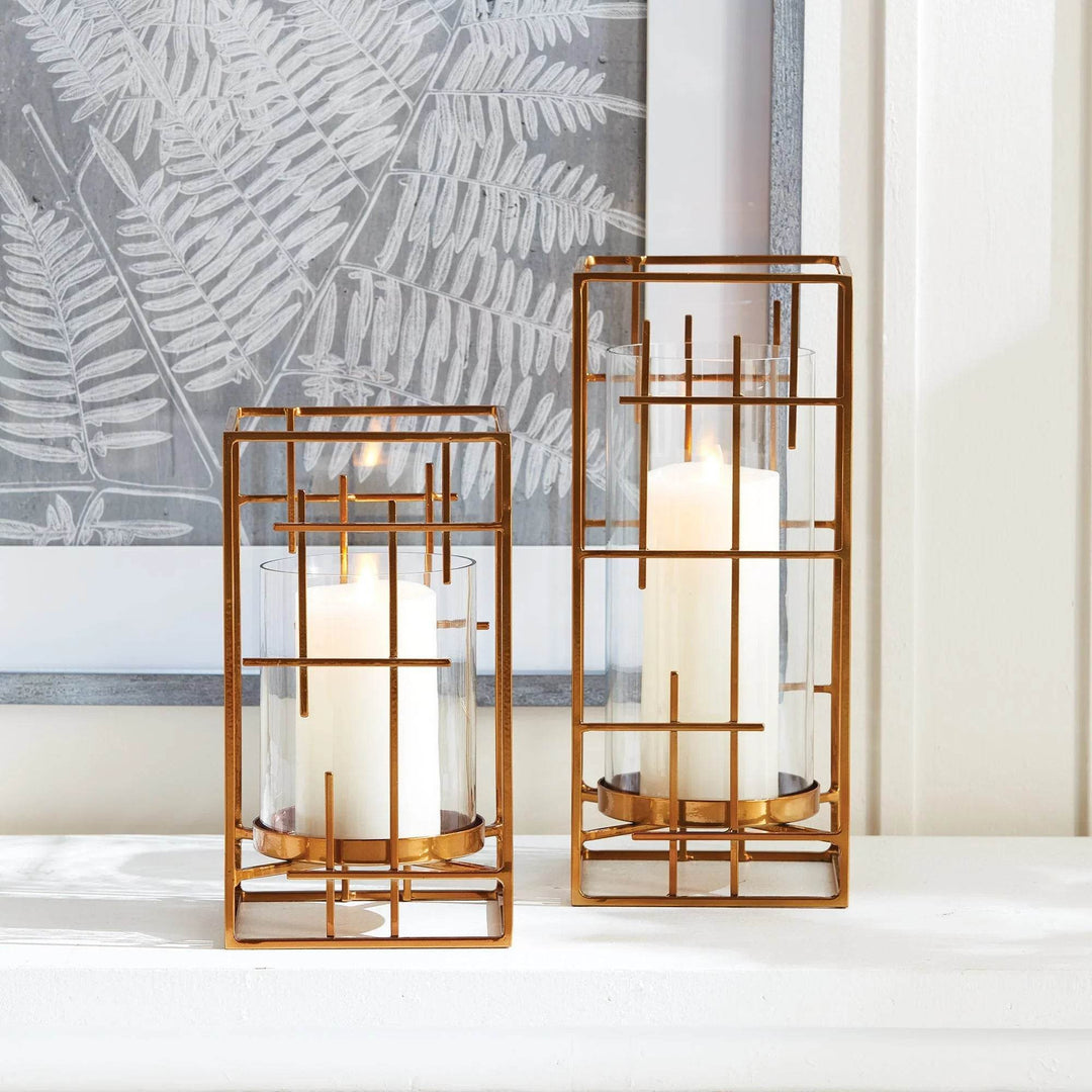 Set of gold hurricane holders with grid-style frames and pillar candles, styled on white mantel – Art Deco Revival

