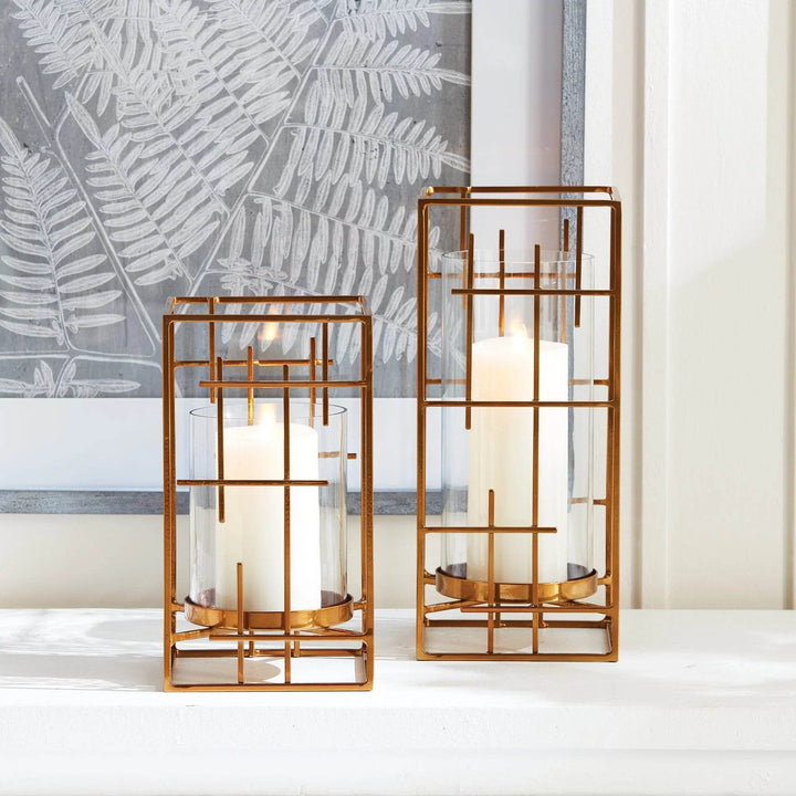 Set of gold hurricane holders with grid-style frames and pillar candles, styled on white mantel – Art Deco Revival

