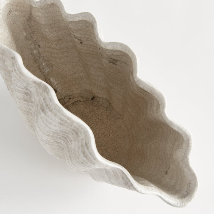 Close view of the wavy cream rim and antiqued interior of a large clay shell vase against a background, Coastal Transitional