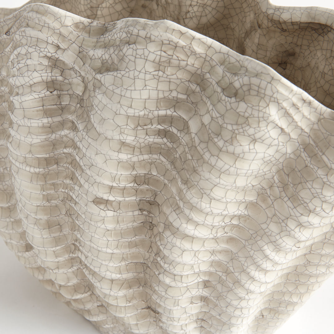 Close view of the crackle glaze and layered shell texture across the cream surface of a large clay vase, Coastal Transitional
