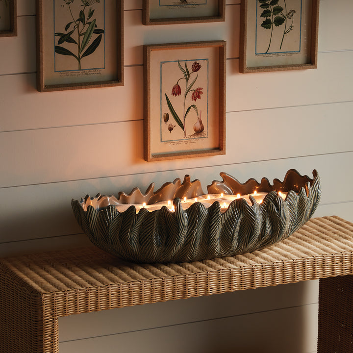 Large decorative oval bowl styled on console with warm lighting sculpted clay statement centerpiece décor style