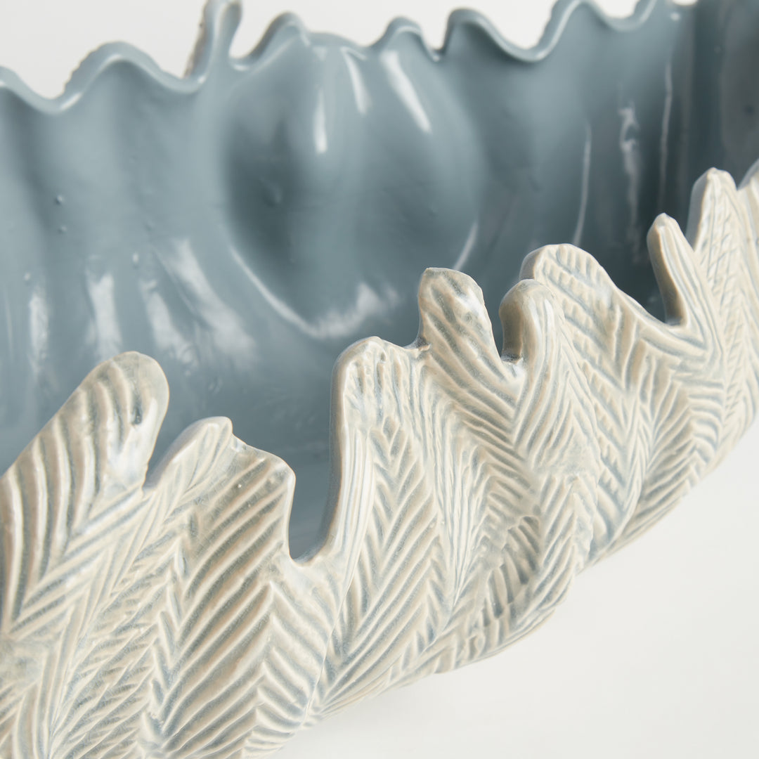 Close view of decorative oval bowl in light blue with textured sculpted exterior and reactive glaze artisan style