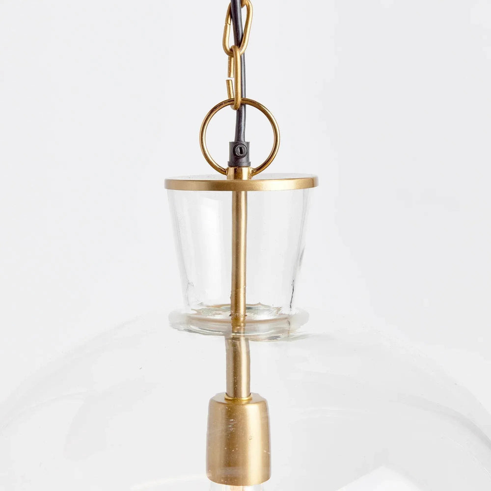 Large glass bell pendant neck close-up showing a clear glass opening, warm metal rim and hanging ring, Transitional style