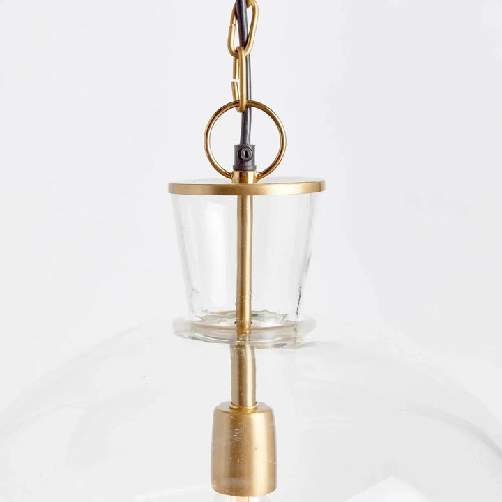 Large glass bell pendant neck close-up showing a clear glass opening, warm metal rim and hanging ring, Transitional style