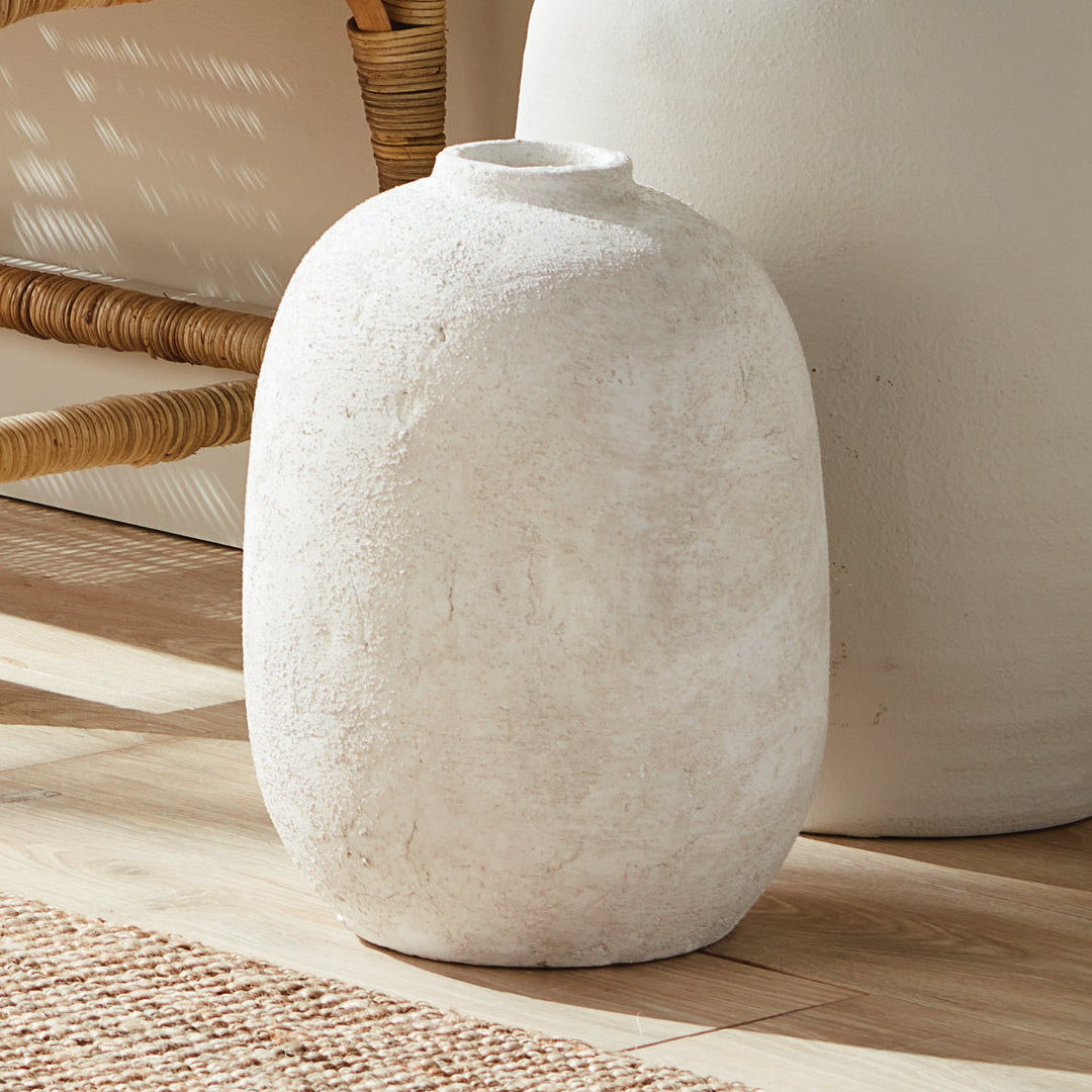 Large gray terracotta vase with textured handcrafted surface styled on floor by natural chair and rug, solid round form – Transitional