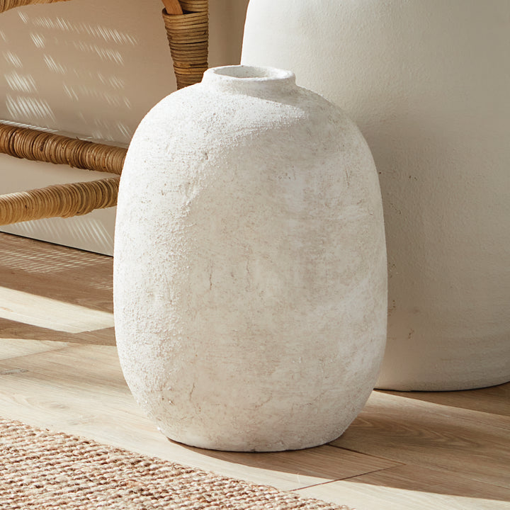 Large gray terracotta vase with textured handcrafted surface styled on floor by natural chair and rug, solid round form – Transitional