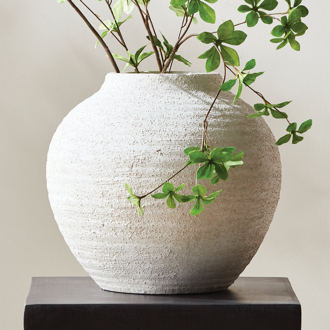 Large gray terracotta vase with handcrafted textured finish styled on dark console with green branches, rounded transitional form – Transitional