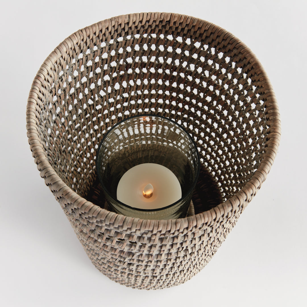 Top view into a large graywash rattan hurricane showing a candle inside its glass insert and the woven sides, Transitional
