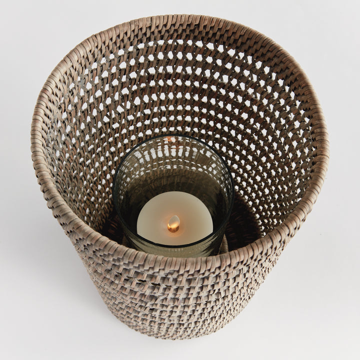 Top view into a large graywash rattan hurricane showing a candle inside its glass insert and the woven sides, Transitional
