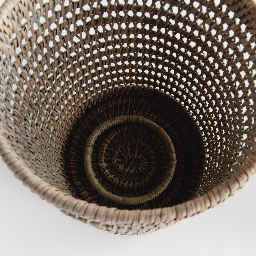 Overhead view into an empty large graywash rattan hurricane showing the woven base and open cylindrical sides, Transitional