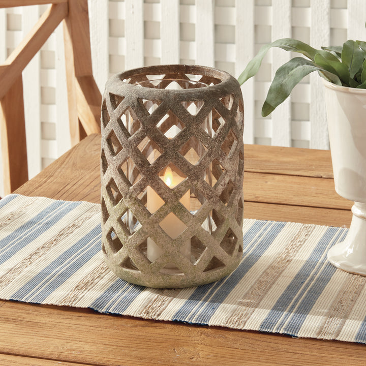 Large moss terracotta hurricane candle holder styled on striped runner with candlelight – Rustic Transitional style.
