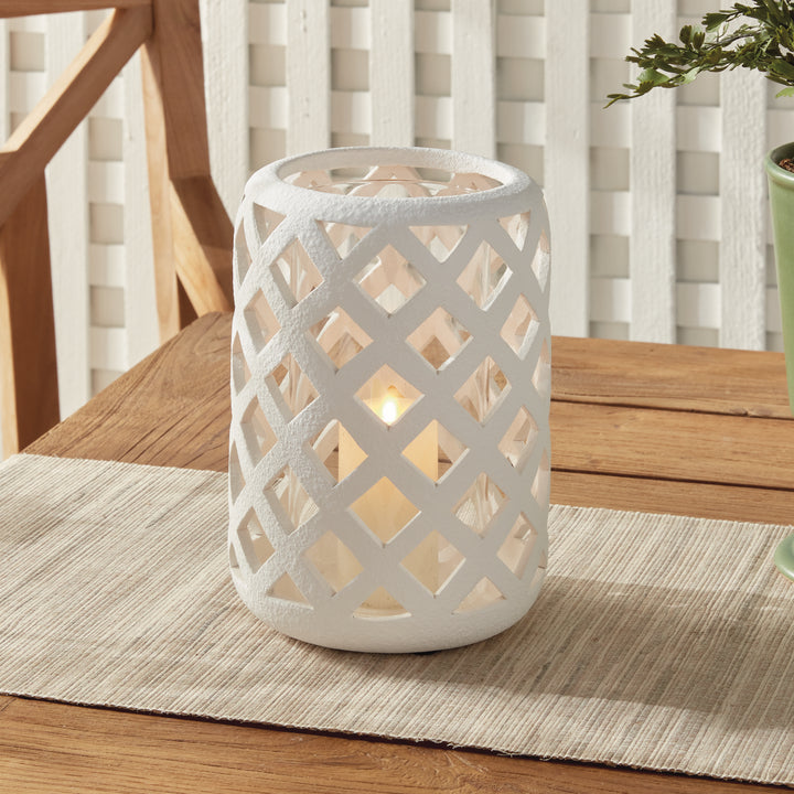 Large white terracotta hurricane candle holder styled on wood tabletop with candlelight – Modern Organic style.