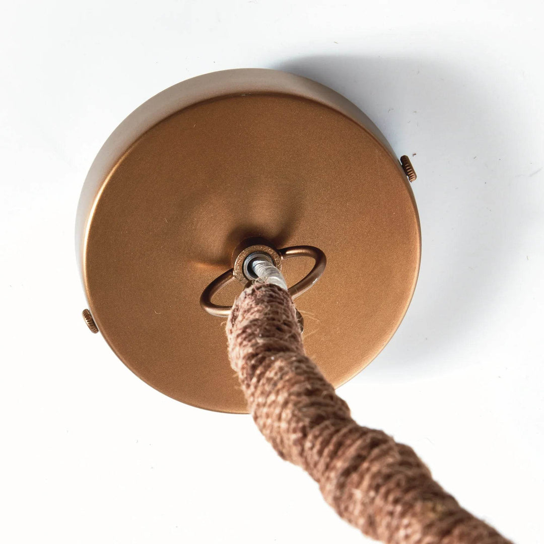 Large rattan pendant ceiling canopy detail showing the round gold-colored plate and natural jute-wrapped chain, Coastal style
