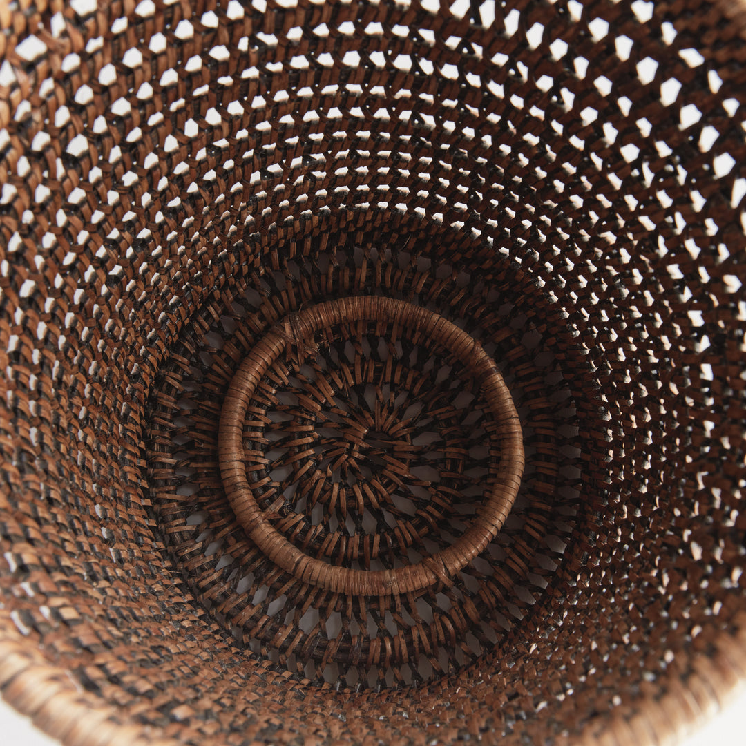 Overhead view into an empty large warm brown rattan hurricane showing the woven base and open cylindrical sides, Transitional