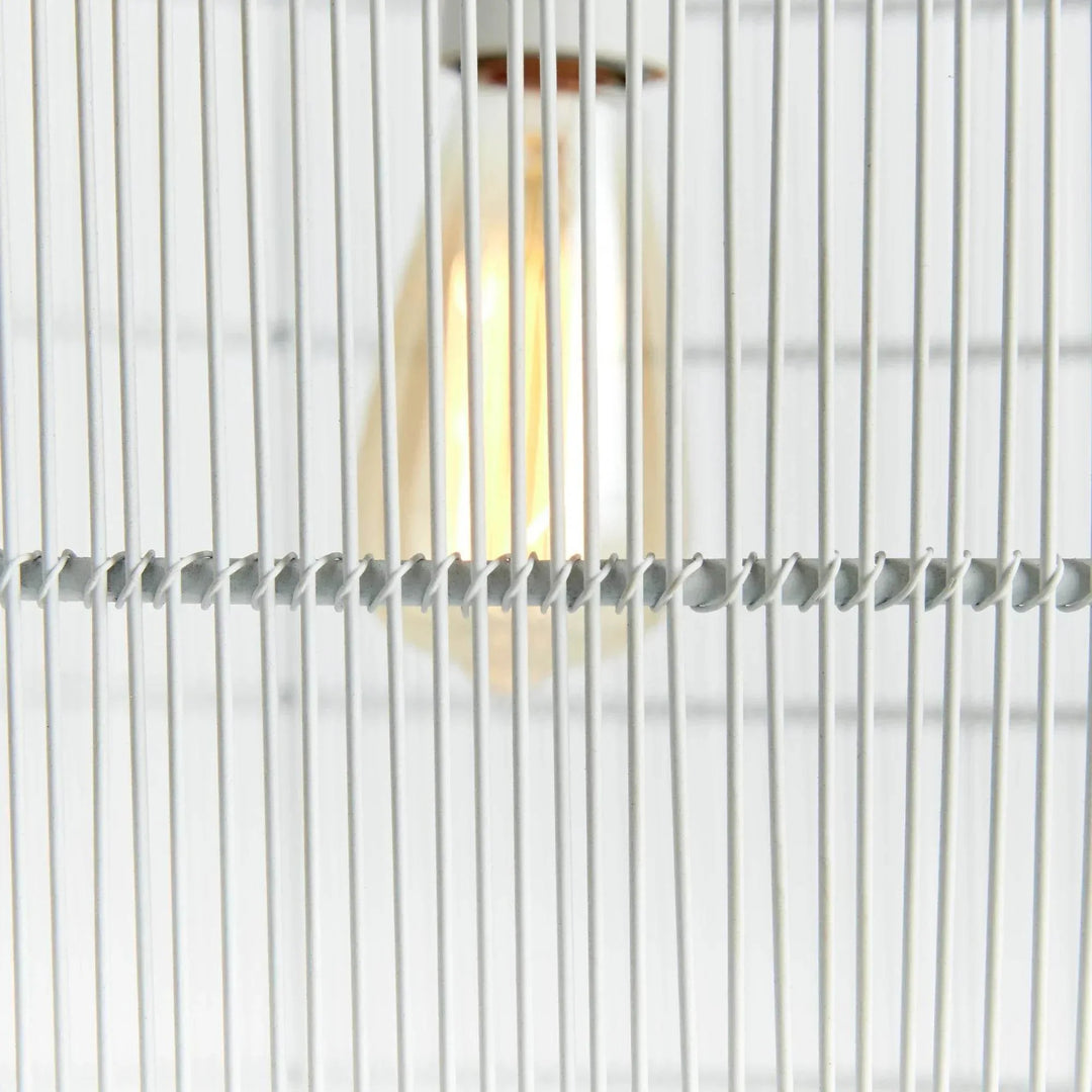 Detail of the large white woven iron pendant light with an exposed bulb visible behind slim vertical strands, Coastal style