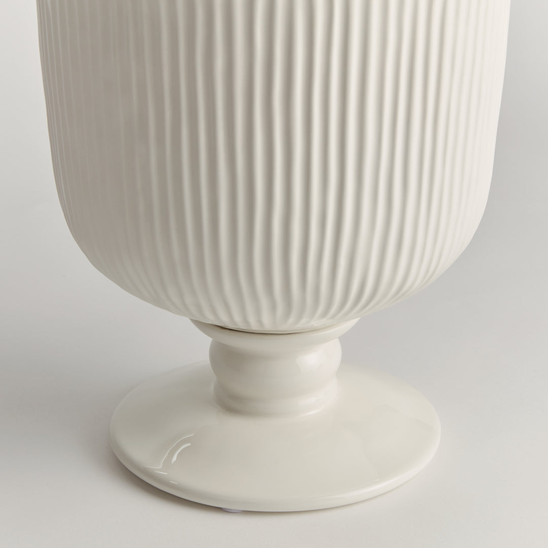 Detail of the large white ceramic footed cachepot showing ribbed sides and a rounded pedestal foot on white, Traditional