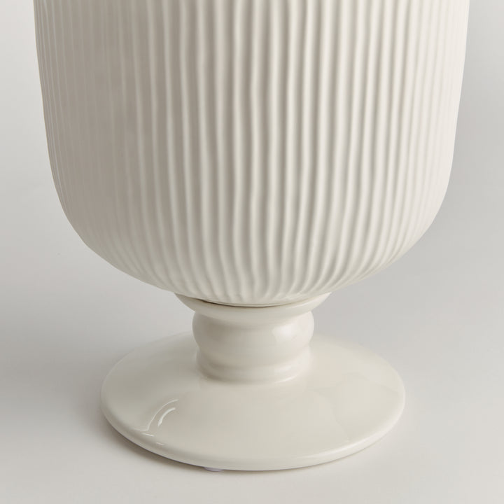 Detail of the large white ceramic footed cachepot showing ribbed sides and a rounded pedestal foot on white, Traditional