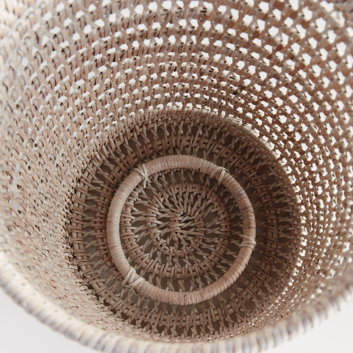 Overhead view into an empty large whitewash rattan hurricane showing the woven base and open cylindrical sides, Transitional