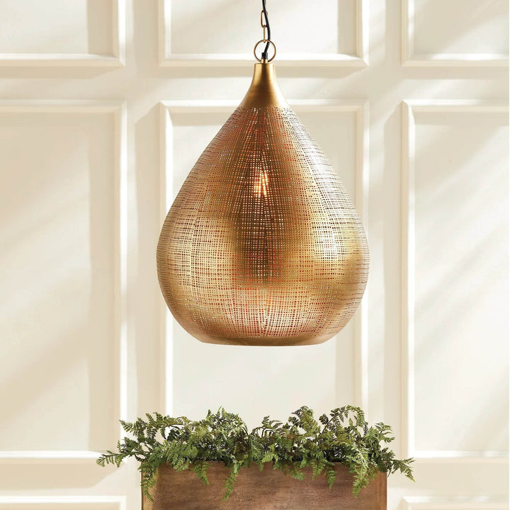 Large gold woven iron teardrop pendant illuminated above a table and greenery, against pale paneled walls, Transitional style