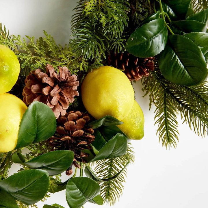 Close-up of faux lemons and pinecones nestled in fir greenery – left side detail