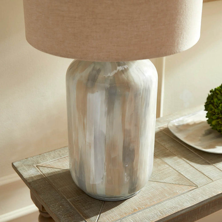 Close-up of hand-painted base and oversized linen shade on coastal-inspired neutral table lamp with artisanal finish.

