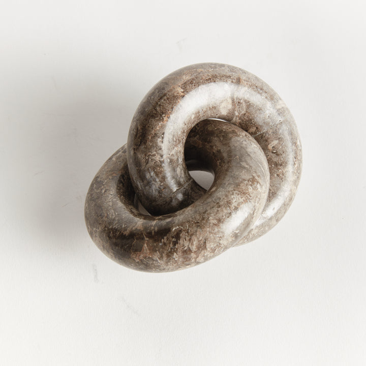 Linked marble rings sculpture in an elevated angled view, showing overlapping loops and gray-brown tones - Modern Organic