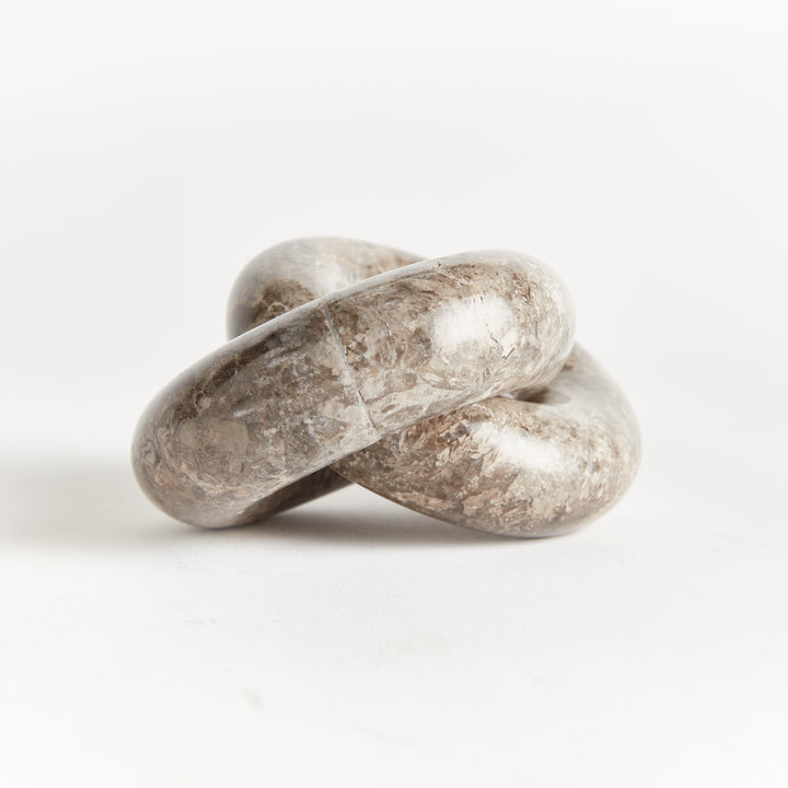 Linked marble rings sculpture seen from a low side angle, showing rounded stone loops and natural veining - Modern Organic
