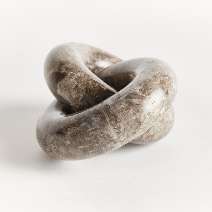 Linked marble rings sculpture in an angled close view, showing brown mineral patterns across curved stone - Modern Organic