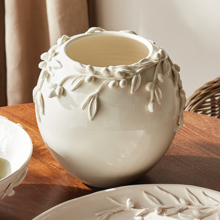 White Italian olive relief vase on a wood table beside coordinating glazed ceramics, with raised branch details. Traditional