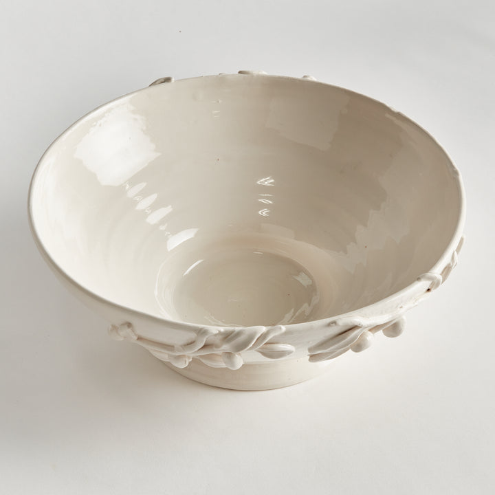 Overhead view of a white ceramic footed bowl, showing its glazed interior and olive details around the outer rim. Traditional