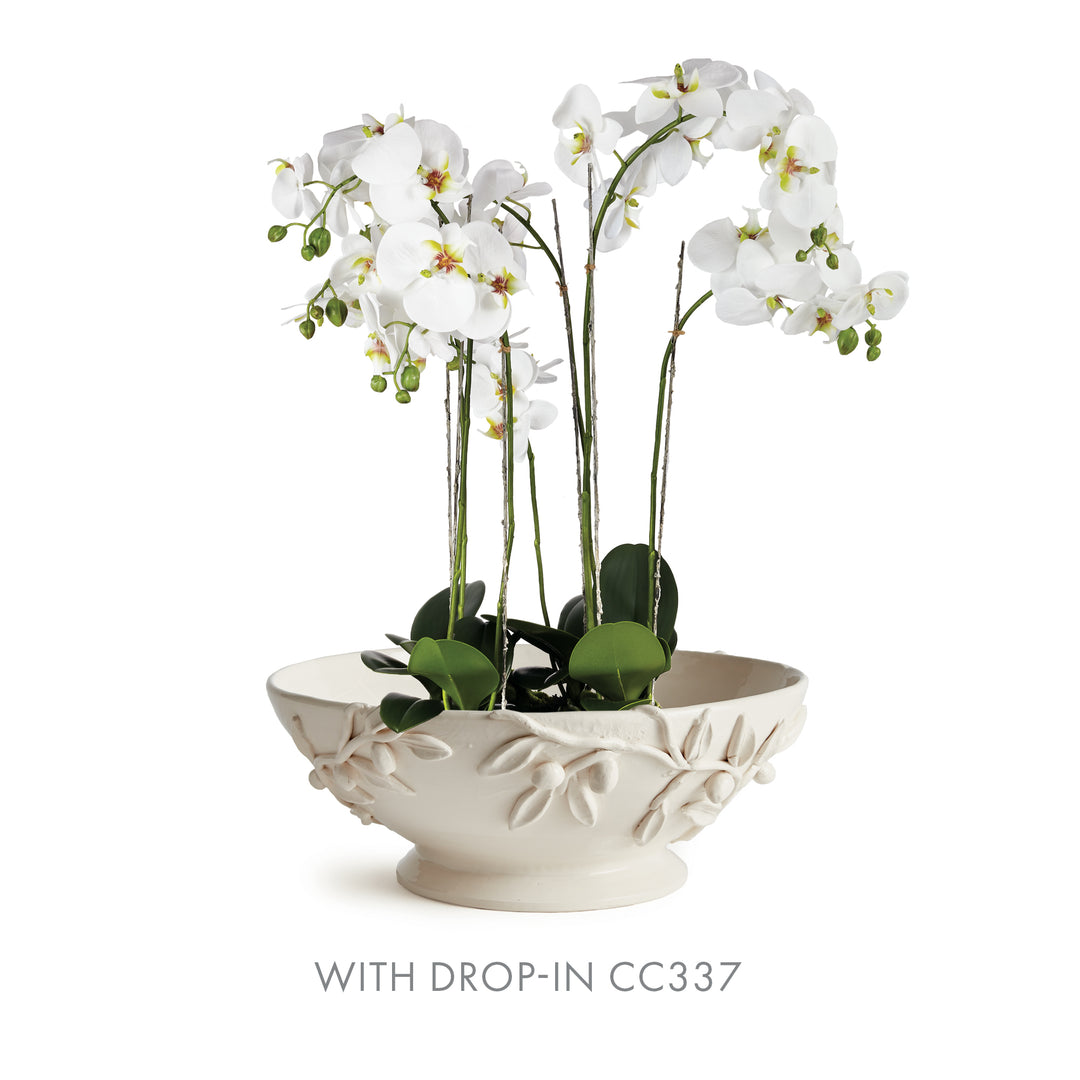White olive relief bowl displayed with a tall white orchid arrangement, with green leaves above its raised rim. Traditional